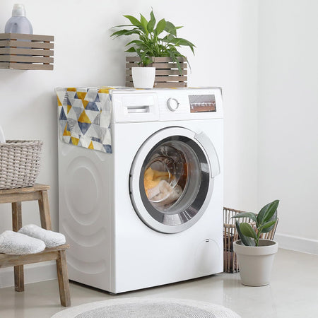 Geometric patterned washer and dryer top cover protector mat with side storage pockets on a white washing machine.